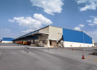 A large warehouse structure sits on a cement tarmac